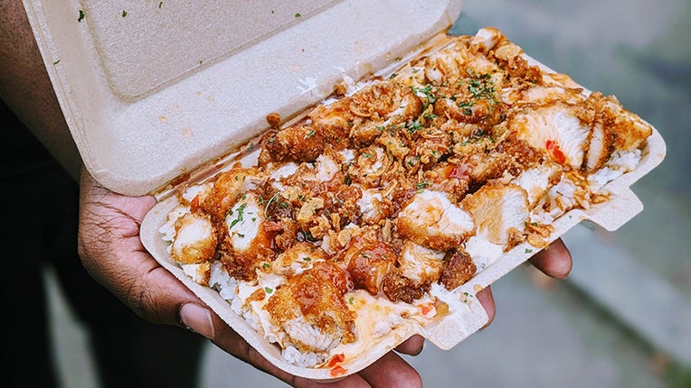 Une barquette de riz et de poulet pané nappé de sauces